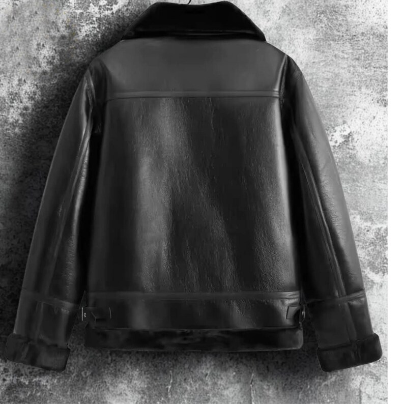 May include: Black leather jacket with a shearling collar and cuffs. The jacket has a classic design with a smooth, glossy finish. The back of the jacket is visible, showcasing the tailored fit and details.