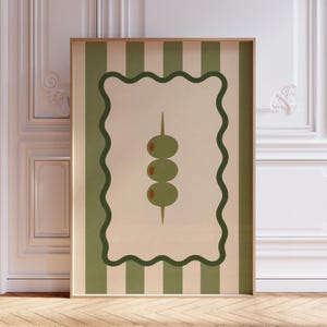 May include: A framed art print featuring a stylized illustration of three green olives on a toothpick. The olives are set against a beige background with a wavy green border, and a green and white striped background.