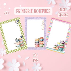 Puede incluir: Blocs de notas imprimibles con tres diseños, cada uno con un borde diferente e ilustraciones de tazas de té. Un bloc de notas tiene un borde de cuadros verdes, otro un borde de lunares morados y el tercero tiene rayas de colores. Los blocs de notas miden 10 x 15 cm.