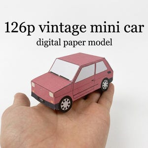May include: A pink paper model of a 126p vintage mini car with white windows, black wheels, and a black front bumper. The text 126p vintage mini car digital paper model is printed above the car in a black serif font on a white background.