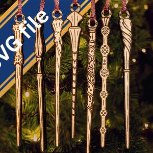 May include: Six hanging wooden wand ornaments with intricate carved details and hanging loops, arranged vertically. The text SVG file is displayed diagonally across the image in white letters over a blue and gold banner background.