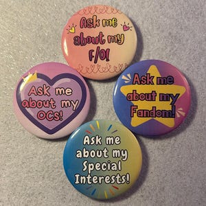 May include: Four colorful round buttons with text. One button says "Ask me about my f/ol" in pink and orange. Another says "Ask me about my OCs!" in pink. A third says "Ask me about my Fandom!" in blue and yellow. The last says "Ask me about my Special Interests!" in blue and yellow.