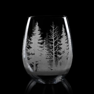 May include: A clear, stemless wine glass with a forest scene etched into the glass. The design features detailed silhouettes of trees, creating a woodland landscape. The glass is ideal for enjoying wine.