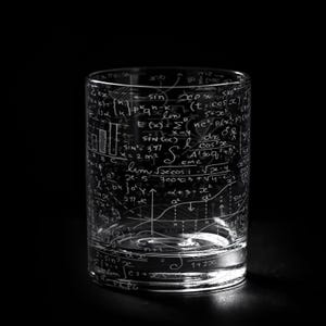 May include: A clear glass tumbler etched with white mathematical equations, formulas, and graphs. The glass is cylindrical with a thick base, and the black background highlights the intricate details of the design. A unique gift for math enthusiasts.