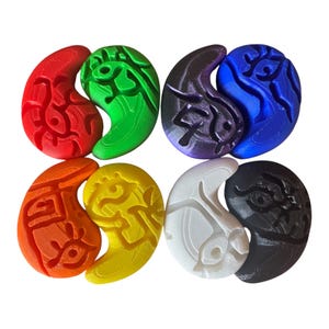 May include: A collection of six 3D-printed Yin and Yang pendants in various colors. The pendants are red, green, purple, blue, orange, yellow, white, and black. Each pendant has a detailed, carved design.