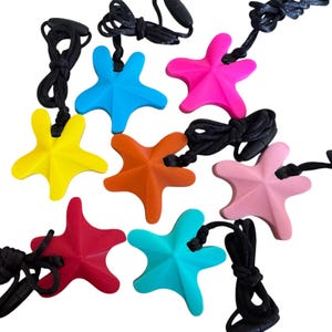 Può includere: Una collezione di ciondoli a forma di stella marina colorati in varie tonalità, tra cui giallo, blu, rosa, arancione, rosso e turchese. Ogni ciondolo è attaccato a un cordino nero con chiusura regolabile. I ciondoli sono in gomma morbida.