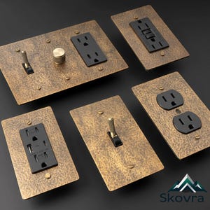 Puede incluir: Una colección de cinco placas de pared eléctricas con acabado en bronce martillado. El conjunto incluye varias configuraciones con enchufes negros, interruptores de palanca, un mando giratorio de atenuación y un puerto USB, fijados con tornillos.
