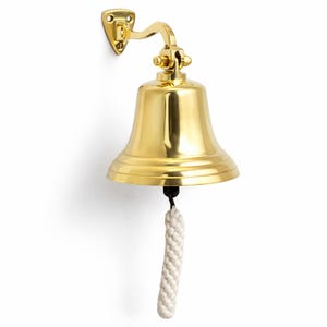May include: A polished brass bell with a curved bracket for wall mounting. The bell has a flared shape and a white rope pull. The bell is a nautical or maritime-themed decorative item.