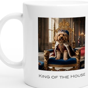 Può includere: Tazza in ceramica bianca con l'immagine di un cane reale seduto su un trono. L'immagine è incorniciata con dettagli dorati e il testo "KING OF THE HOUSE" è stampato sotto. La tazza ha un manico curvo. Il cane indossa una corona e un mantello.