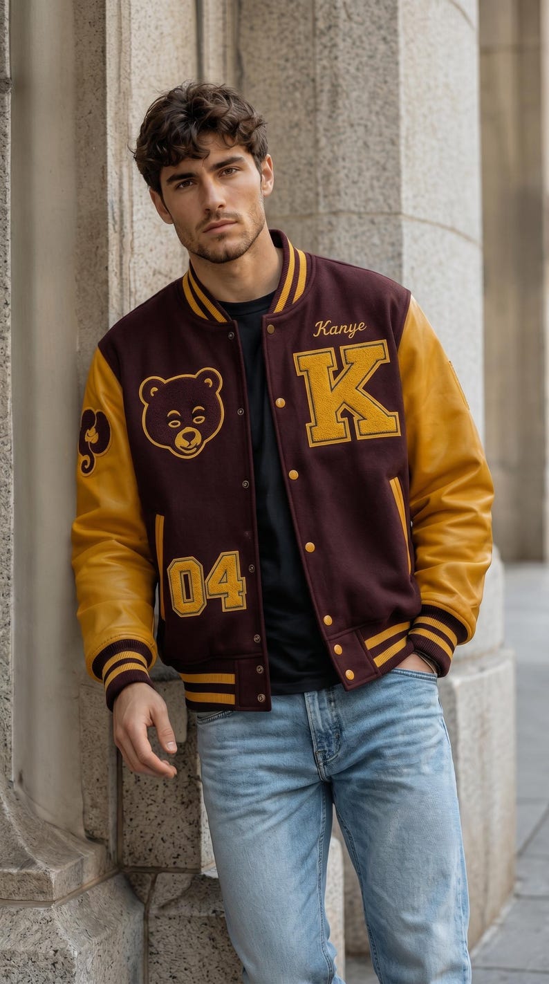 Puede incluir: Chaqueta universitaria granate y dorada con mangas de cuero. La chaqueta presenta el nombre "Kanye" y la letra "K" en dorado, junto con un gr&aacute;fico de oso y el n&uacute;mero "04".