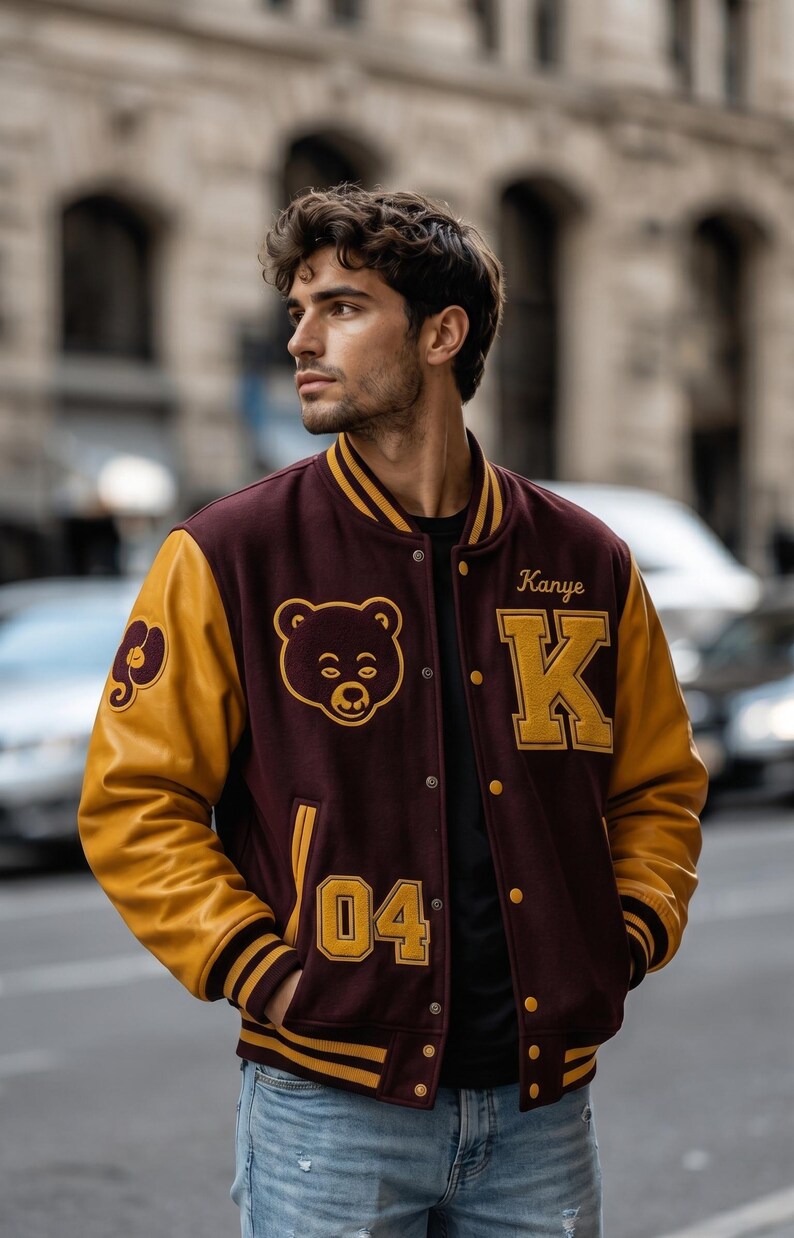 Puede incluir: Chaqueta universitaria granate y dorada con un logotipo de oso y el nombre "Kanye" y la letra "K" en dorado. La chaqueta tiene mangas doradas y el n&uacute;mero "04" en la parte delantera.
