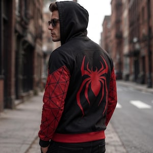 May include: Black hooded jacket with red accents and a large red spider emblem on the back. The sleeves feature a geometric red pattern. The jacket has a red band at the waist and cuffs.