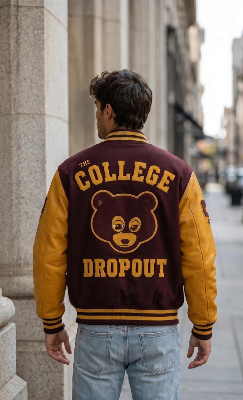 Puede incluir: Chaqueta universitaria granate y dorada con el texto "THE COLLEGE DROPOUT" y un gr&aacute;fico de oso en la espalda. La chaqueta tiene mangas doradas y pu&ntilde;os y dobladillo a rayas. La persona lleva vaqueros azul claro.
