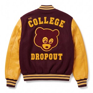 Puede incluir: Chaqueta universitaria granate y dorada con la inscripci&oacute;n "THE COLLEGE DROPOUT" y un gr&aacute;fico de oso. La chaqueta tiene mangas de cuero dorado y pu&ntilde;os y cuello a rayas.