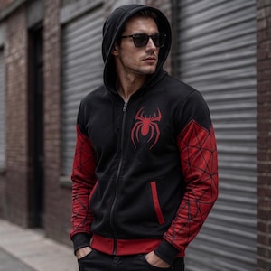 May include: Black zip-up hoodie with a red spider emblem on the chest. The sleeves are red with a black web design. The hoodie has a hood and a red trim along the bottom and pockets.