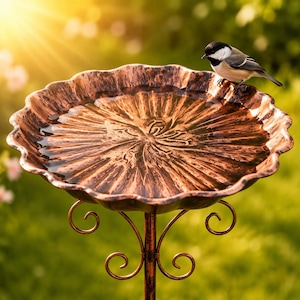 May include: A copper-colored bird bath with a scalloped edge and a textured, radial pattern in the basin. The basin is supported by a metal stand featuring decorative scrollwork. A small black, white, and gray chickadee perches on the rim.