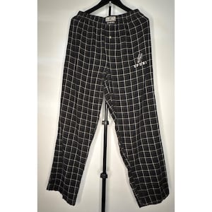 May include: Black and white checked pajama trousers with a button fastening and a small embroidered "SPURS" logo. The trousers are suspended on a black hanger against a white backdrop.