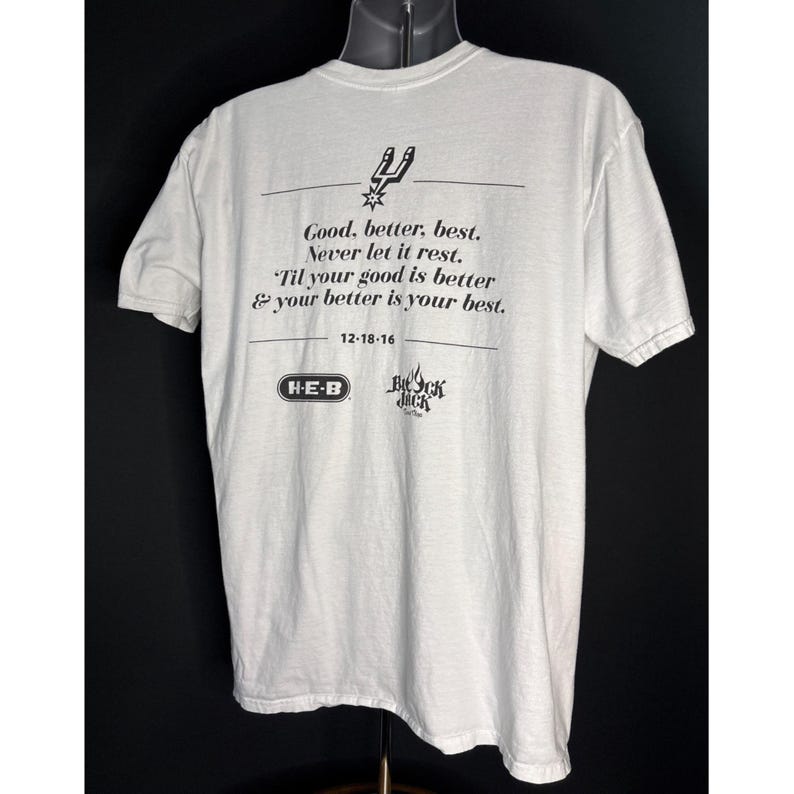 May include: White t-shirt with black text and graphics. The text reads "Good, better, best. Never let it rest. 'Til your good is better & your better is your best." Includes the date 12-18-16 and the logos of H-E-B and Beck Jack.