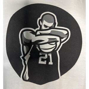 May include: A black and white graphic of a basketball player in a stylized pose, set against a black circular background. The player is wearing a jersey with the number 21. The image is a simple, bold design.