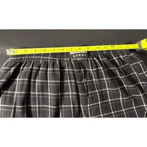 May include: Black and white plaid boxer shorts with the word "SPURS" on the waistband. The shorts are measured with a yellow tape measure, showing a length of approximately 28 cm.