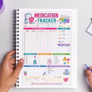 Op de afbeelding: Een spiraalgebonden medicatietracker-notitieboek met een kleurrijk ontwerp. De omslag toont de woorden "Medication Tracker" en een hartafbeelding. Binnenin zijn er secties voor dagelijkse logs, herinneringen en artsinformatie. Het notitieboek wordt door een persoon vastgehouden.