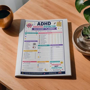 May include: ADHD Executive Dysfunction Recovery Planner on a wooden table. The planner has sections for daily priorities, executive function check-in, task breakdown, and a time block plan. The planner's design includes colorful graphics and text.
