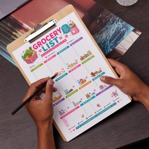 Może przedstawiać: Drewniana tablica z kolorową listą zakupów zatytułowaną "Grocery List". Lista zawiera sekcje na produkty, nabiał, przekąski i inne, z ilustracjami produktów spożywczych. Ręka trzyma czarny długopis, gotowy do pisania.