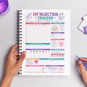 Op de afbeelding: Een spiraalgebonden IVF-injectietracker-notitieboek met een kleurrijke lay-out. De omslag toont de tekst "IVF INJECTION TRACKER" met decoratieve harten en bloemelementen. De binnenkant bevat secties voor injectieschema's, medicatie-informatie en dagelijkse symptoomtracking.