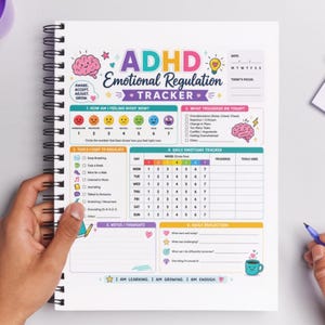May include: A spiral-bound ADHD emotional regulation tracker with colorful illustrations and text. The tracker includes sections for daily mood, triggers, and tools used, along with prompts for self-reflection and notes. The cover features the text "ADHD Emotional Regulation Tracker."