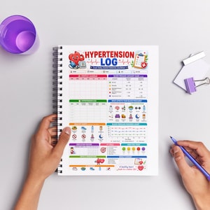 May include: A spiral-bound notebook with a colorful "Hypertension Log" cover. The log includes sections for tracking blood pressure, medication, and healthy habits. A purple cup and pen are visible.