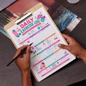 以下が含まれることがあります： 木製のクリップボードには、カラフルな「DAILY EXERCISE LOG」シートが入っています。シートには、ワークアウトの詳細、カーディオ、水分摂取量、メモのセクションがあります。デザインには、ウェイト、ランニングシューズ、ウォーターボトルのイラストが含まれています。手は黒いペンを持っています。