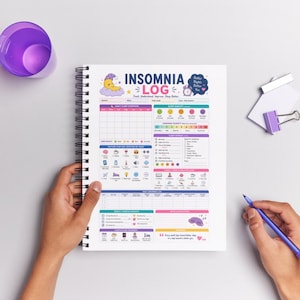 Peut inclure: Un cahier Insomnia Log à spirales avec une mise en page colorée. La couverture présente le titre "Insomnia Log" et une lune de dessin animé. Le cahier est ouvert, révélant des sections détaillées pour suivre les habitudes de sommeil. Une tasse violette et un stylo sont également visibles.