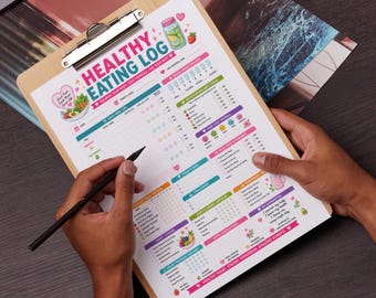 May include: A wooden clipboard holds a colorful "Healthy Eating Log" sheet. The log features sections for daily meals, mood tracking, and goals. A black pen is held over the sheet, ready to write. The log includes illustrations of fruits and vegetables.