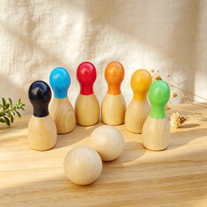 以下が含まれることがあります： 木製のボーリングセット。6本のピンと2つのボールがあります。ピンは天然木でできており、黒、青、赤、オレンジ、黄色、緑のカラフルなトップが付いています。ボールも木製です。