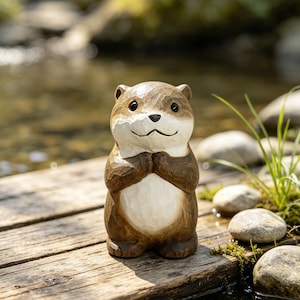 May include: A hand-carved wooden figurine of an otter with a brown and white finish. The otter is depicted in a standing position with its front paws held together near its chest, featuring carved texture details and smooth, dark eyes.