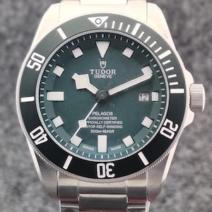 Op de afbeelding: Een roestvrijstalen Tudor Pelagos horloge met een donkergroene wijzerplaat en een zwarte draaibare bezel. De wijzerplaat toont de merknaam, modeldetails en is waterdicht tot 500m. Het horloge heeft een datumweergave op 3 uur.