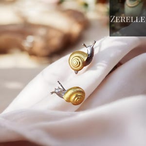 Op de afbeelding: Een set van drie keramische mokken met een gespikkelde, matte afwerking. De mokken zijn in crème, lichtbruine en donkerbruine tinten. Elke mok heeft een eenvoudig, minimalistisch ontwerp en een afgeronde handgreep.