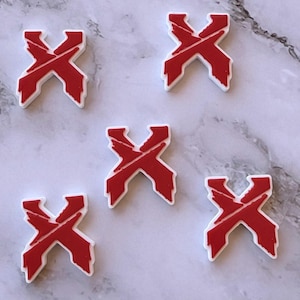 May include: Five individual shoe charms, each shaped like a stylized letter X. The charms feature a vibrant red top layer with a jagged, distressed texture and a solid white base layer, creating a distinct contrast in color and depth for each piece.