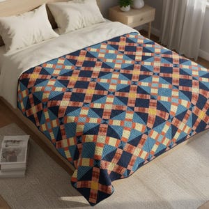 Puede incluir: Una colcha con estampado geométrico en tonos azul marino, azul, naranja y amarillo cubre una cama. La colcha presenta un diseño repetitivo de diamantes y cuadrados. Se ven dos almohadas blancas y una sábana color crema.