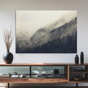 May include: A modern living room featuring a large landscape painting above a wooden media console. The console has glass-fronted cabinets and open shelving. A black vase with dried branches and two black decorative bottles are also present.