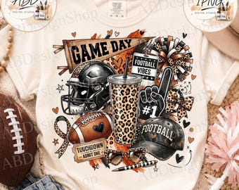May include: A cream-coloured t-shirt featuring a graphic print with a football helmet, a leopard print tumbler, a football, a #1 foam finger, a baseball cap labelled FOOTBALL, heart-shaped sunglasses, a pennant reading GAME DAY, and a sign saying TOUCHDOWN ADMIT ONE.