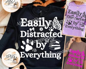 May include: A black sweatshirt featuring white text that reads Easily Distracted by Everything, accompanied by graphic icons of a butterfly, a paw print, a small bow, a flower, and a stack of books. Two smaller shirt variations are also visible.