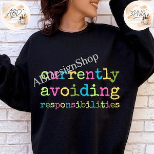 May include: A black long-sleeve crewneck sweatshirt featuring the text "currently avoiding responsibilities" printed in a distressed, multi-colored font. The letters alternate between bright shades of lime green, hot pink, and cyan blue.