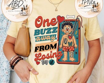 May include: A pale yellow t-shirt featuring a graphic of a person with a red clown nose inside a rectangular frame. The text reads One BUZZ away FROM Losing it. The design includes a pair of tweezers, a heart, a butterfly, and a bone.