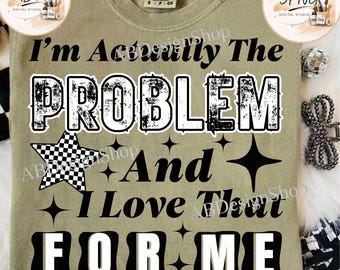 May include: A sage green t-shirt featuring black text that reads I'm Actually The PROBLEM And I Love That FOR ME. The design includes a black and white checkered star and several four-pointed star icons. The shirt has a crew neck and short sleeves.