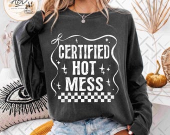 May include: A charcoal grey long-sleeve sweatshirt featuring a white graphic print with the text "CERTIFIED HOT MESS" in a distressed font, surrounded by a wavy border, small star accents, and a checkered pattern at the bottom of the design.