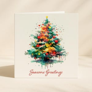 Könnte beinhalten: Weihnachtskarte mit einer Aquarellillustration eines geschmückten Weihnachtsbaums. Der Baum ist mit roten, gelben und orangenen Kugeln geschmückt. Die Worte "Seasons Greetings" sind in roter Schrift unten auf weißem Hintergrund geschrieben.