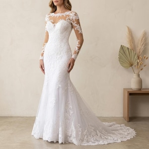 Puede incluir: Vestido de novia blanco, largo hasta el suelo, con intrincados detalles de encaje. El vestido presenta un corpiño ajustado, mangas largas y una silueta de sirena que se ensancha en las rodillas. El escote es transparente y el vestido tiene una larga cola.