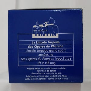 May include: A blue box featuring the Tintin logo and text in French. The text includes "La Lincoln Torpedo des Cigares du Pharaon" and "Lincoln torpedo grand sport ann&eacute;es 30". The box is for adult collectors.