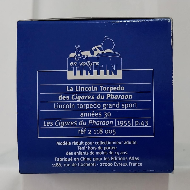 May include: A blue box featuring the Tintin logo and text in French. The text includes "La Lincoln Torpedo des Cigares du Pharaon" and "Lincoln torpedo grand sport ann&eacute;es 30". The box is for adult collectors.